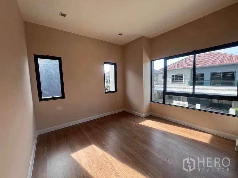 Detached House for sale in Bang Kruai, Nonthaburi - Sunlit upstairs bedroom with large corner windows, wood flooring and neighborhood outlook.