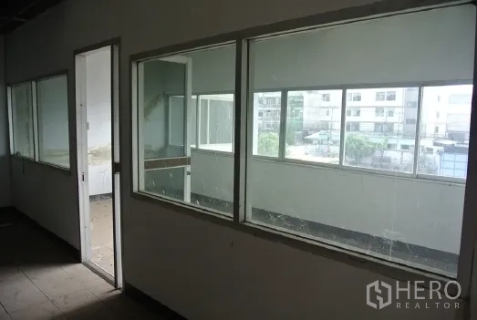 Factory for sale in Bang Phli, Samut Prakan - Corridor with large glass windows and door overlooking the yard.