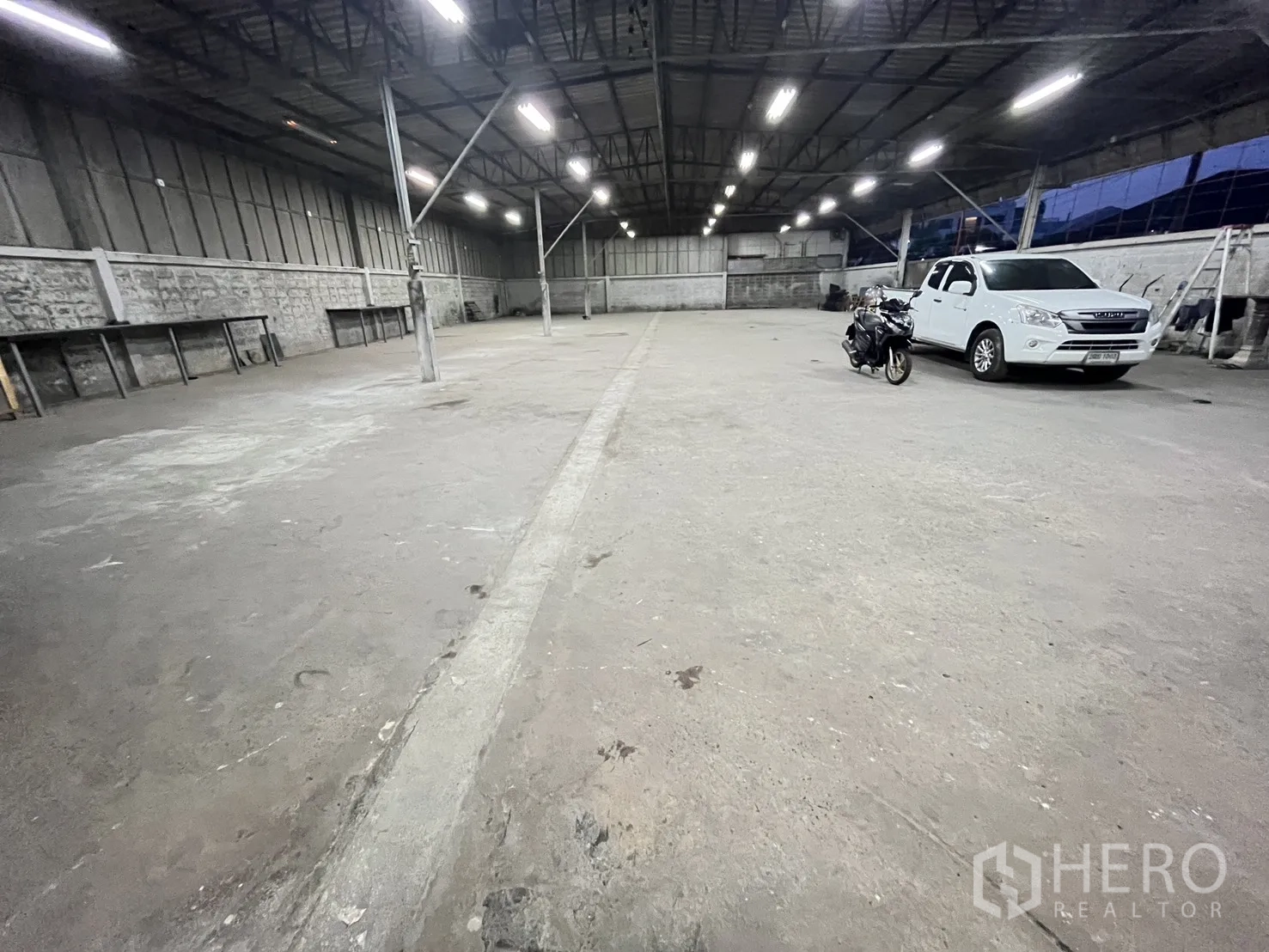 Warehouse for rent in Chatuchak, Bangkok - Open warehouse floor with support columns and parked pickup truck and motorcycle.