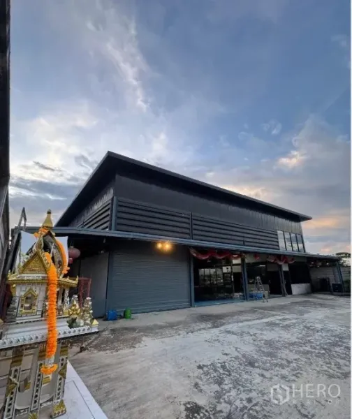 Warehouse for sale in Thanyaburi, Pathum Thani - Wide-angle view of modern warehouse showing multiple shutter doors and ample parking area.