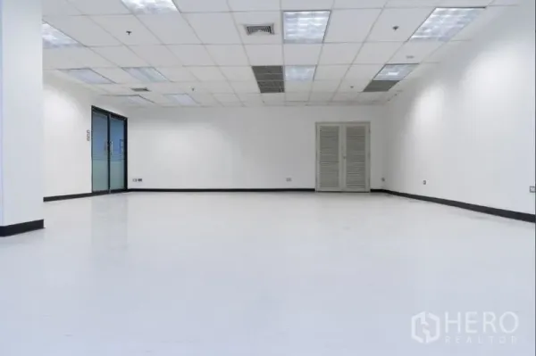 Office Space for rent in Ratchathewi, Bangkok - Spacious white office interior with grid ceiling, air-conditioning vents, glass entry doors and a utility closet.