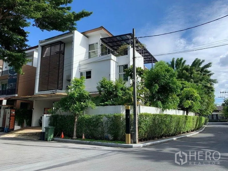 独立式住宅 出售在Suan Luang, Bangkok - 转角地块的现代三层独栋别墅，带露台与绿篱围合。