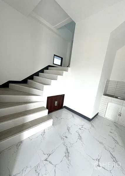 Warehouse for rent in Khlong Luang, Pathum Thani - Interior stairwell beside a small pantry with white cabinetry and tiled flooring.