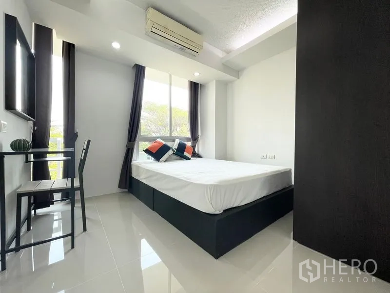Condominium for rent in Khlong Toei, Bangkok - Bright bedroom with double bed, desk, large window, and air conditioner.