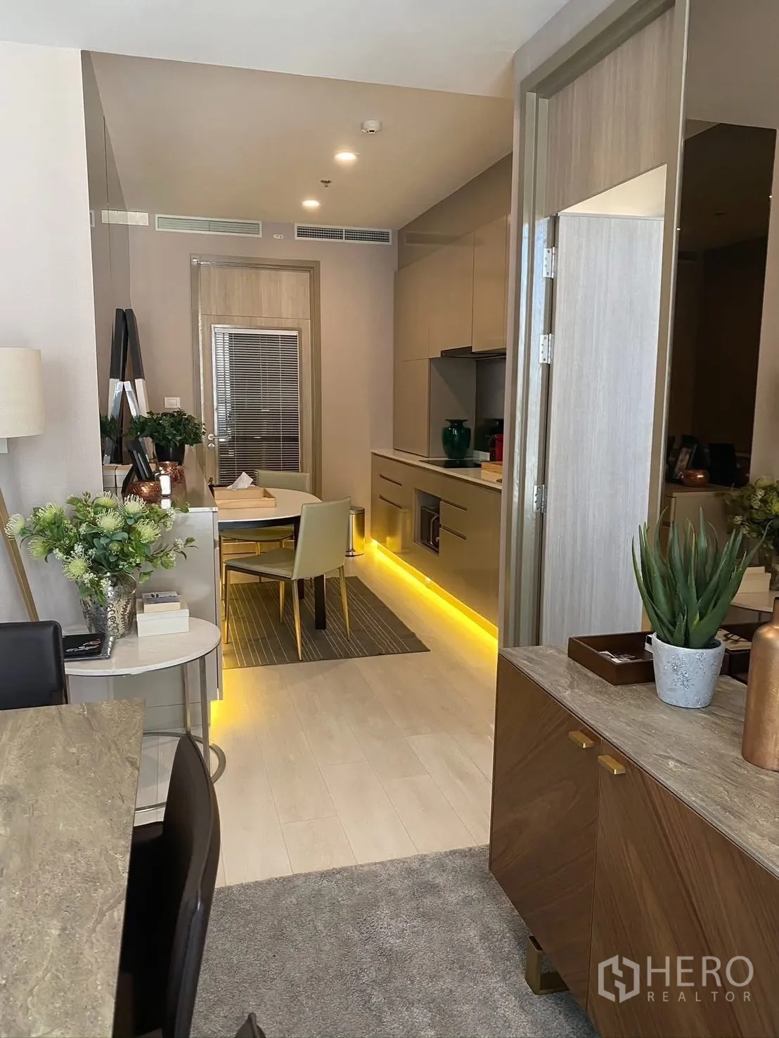 Condominium for rent in Pathum Wan, Bangkok - Open-plan view from living area to kitchen with light wood floors and accent lighting.