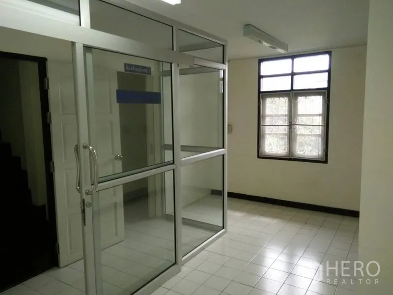 Townhouse for rent in Phra Khanong, Bangkok - Room with aluminum‑frame glass sliding partition beside a window and corridor.