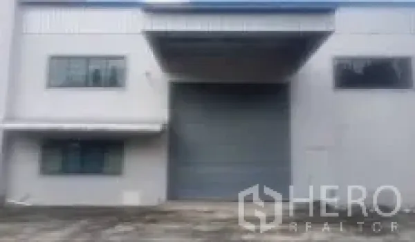 Factory for sale in Lam Luk Ka, Pathum Thani - Loading dock with a large roller shutter door and wide driveway for truck access.