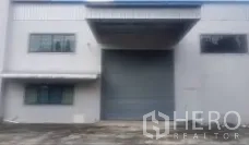 Factory for sale in Lam Luk Ka, Pathum Thani - Loading dock with a large roller shutter door and wide driveway for truck access.