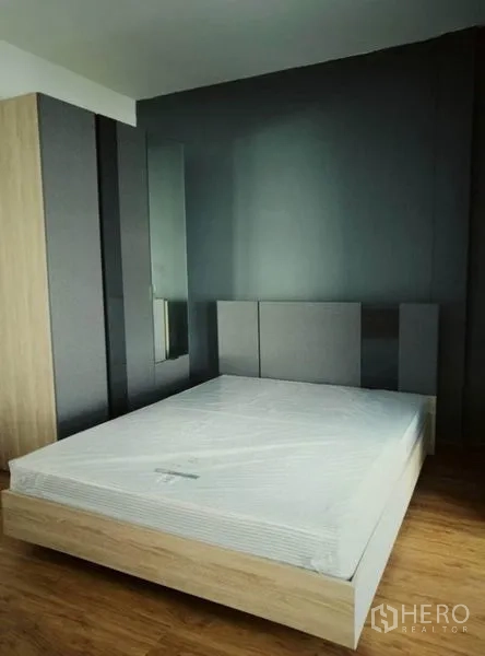 Townhouse for rent in Suan Luang, Bangkok - Bedroom with gray feature wall, wardrobe and a queen bed.