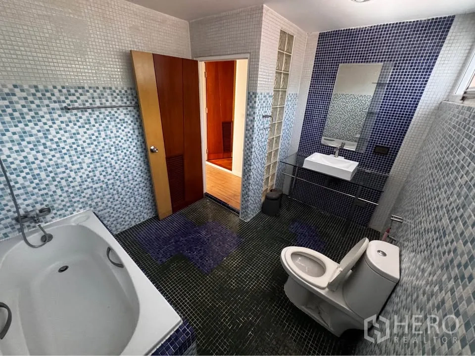 Townhouse for rent in Huai Khwang, Bangkok - Mosaic-tiled bathroom featuring bathtub, toilet and sink.