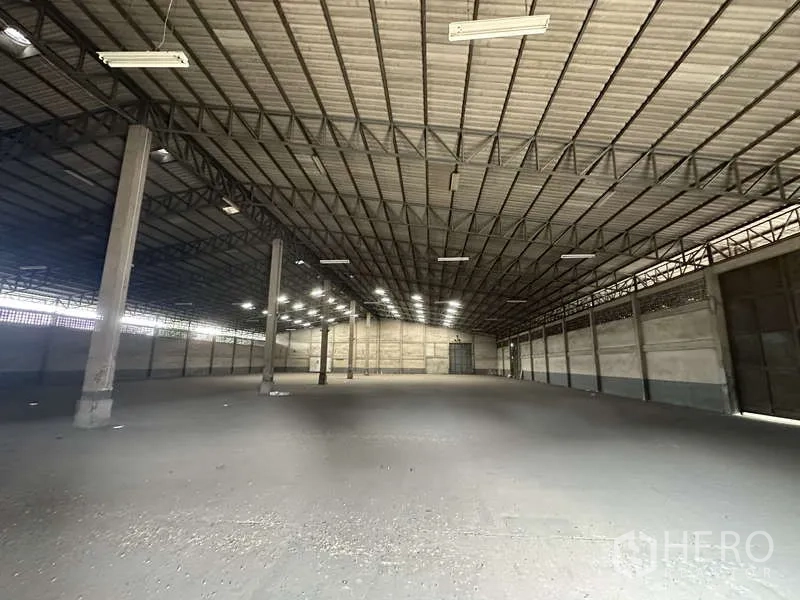 Warehouse for rent in Pak Kret, Nonthaburi - Open-span storage hall showing clear height, concrete floor and large access doors.