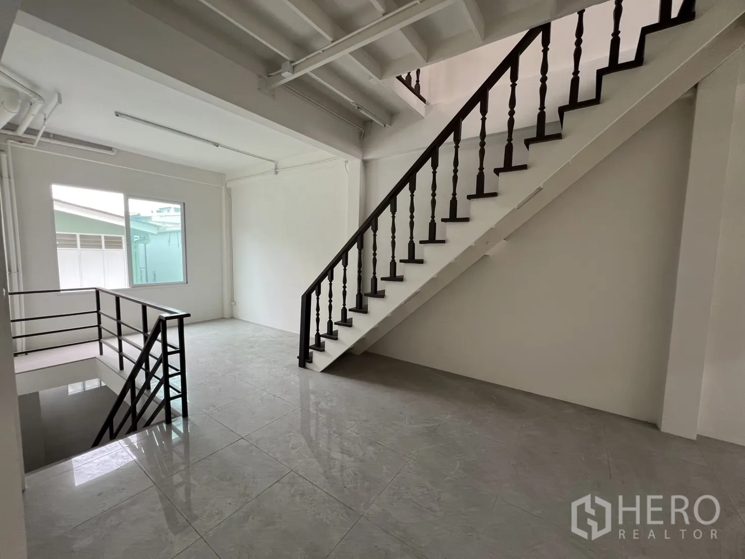 Shophouse for rent in Khlong Toei, Bangkok - Landing area with staircase, window and glossy floor tiles.
