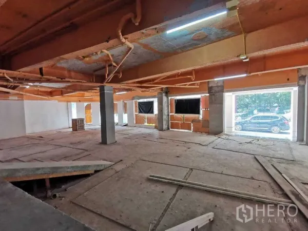 Retail Space for rent in Khlong Toei, Bangkok - Open-plan retail unit with large street-facing windows and orange ceiling beams under renovation.