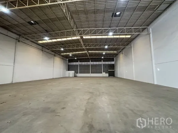 Factory for rent in Khlong Luang, Pathum Thani - Empty production hall with bright lighting, smooth concrete floor, and wide open layout.