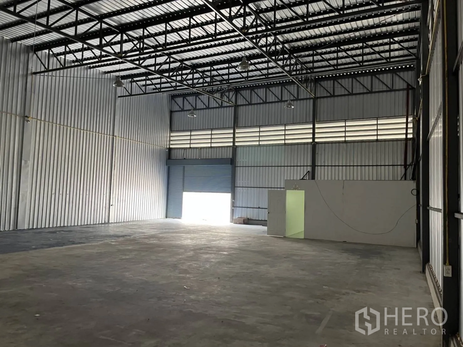 Warehouse for rent in Bang Phli, Samut Prakan - Open interior with shutter entry and an office partition for administration.