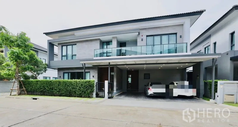 Detached House for rent in Bang Phli, Samut Prakan - Modern two-storey detached house with glass balcony and a covered two-car carport.