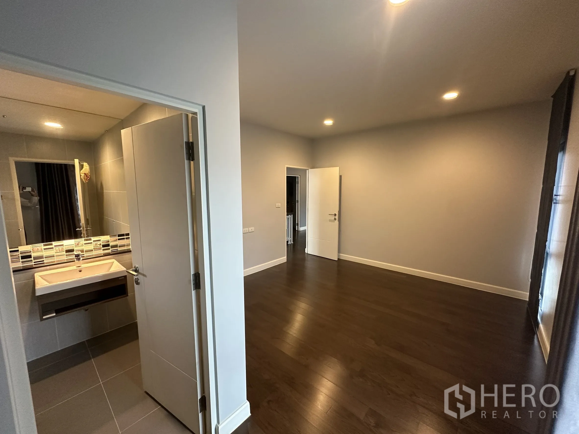 Detached House for rent in Lam Luk Ka, Pathum Thani - Ensuite bedroom with wood flooring and sink area by the door.
