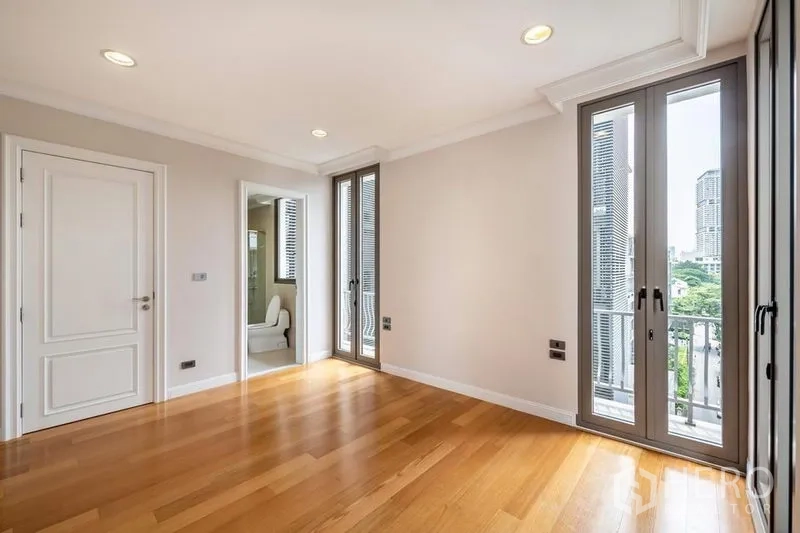 Townhouse for rent in Khlong Toei, Bangkok - Corner bedroom with en-suite bathroom, tall windows and balcony doors.