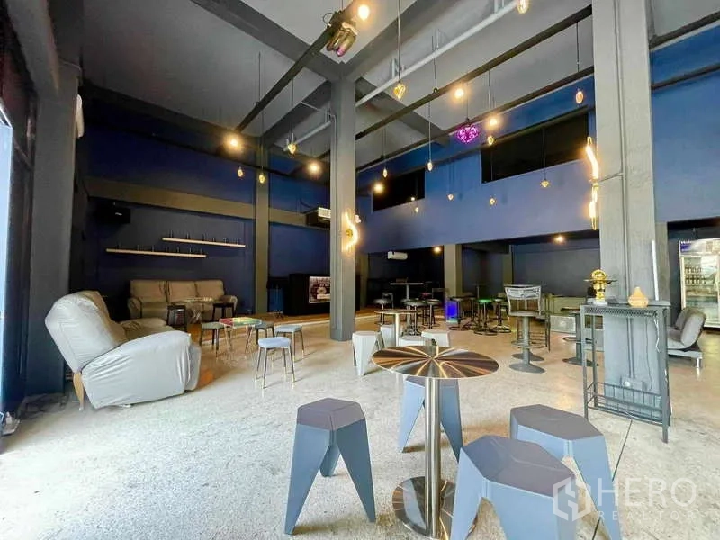 Shophouse for rent in Lat Phrao, Bangkok - Open-plan café-style space with high ceiling, stools and modern hanging lights.