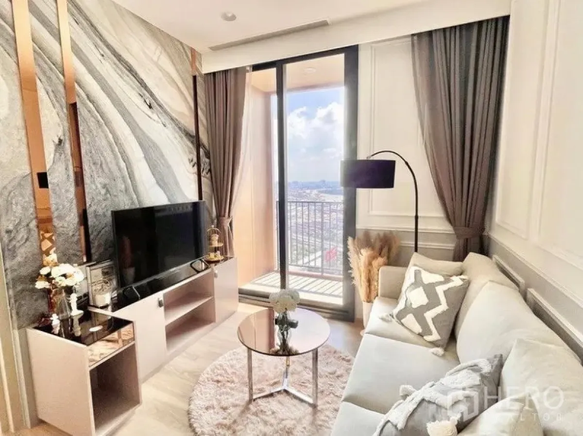 Condominium for rent in Khlong Toei, Bangkok - Bright living room with marble feature wall, TV console and sliding glass doors opening to a balcony with skyline views.
