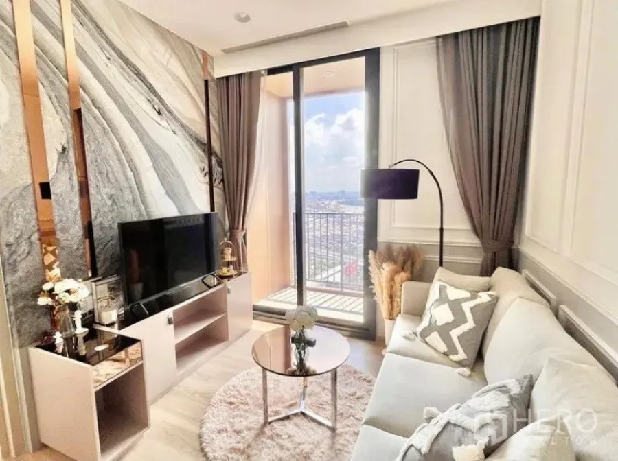 Condominium for rent in Khlong Toei, Bangkok - Bright living room with marble feature wall, TV console and sliding glass doors opening to a balcony with skyline views.