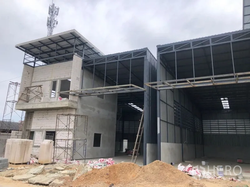 Warehouse for rent in Lam Luk Ka, Pathum Thani - Twin warehouse bays with large covered loading areas and steel frames under construction.