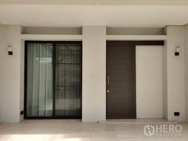 Townhouse for rent in Suan Luang, Bangkok - Close-up of the main entrance with sliding glass door and a solid wood front door