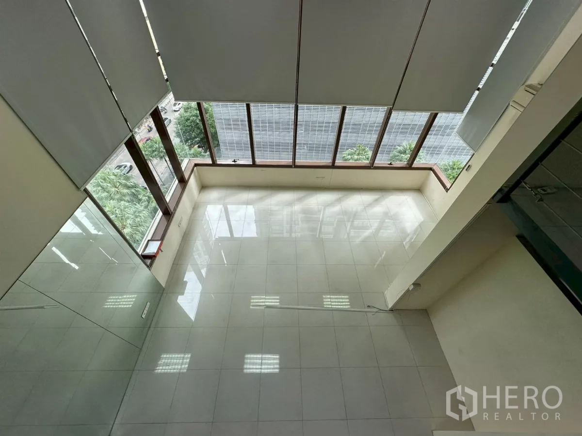 Office Space for rent in Khlong Toei, Bangkok - Top-down view of the double-height area with full-height windows and street trees outside.