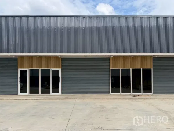 货栈 出租在Suan Luang, Bangkok - 新建仓库外立面，金属板墙、卷闸与玻璃门，前方宽阔混凝土场地（曼谷Suan Luang）。
