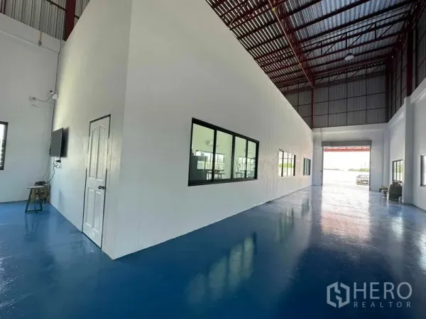 Warehouse for sale in Khlong Luang, Pathum Thani - Spacious warehouse interior with high red-steel roof and epoxy blue floor.