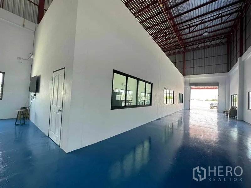 Warehouse for sale in Khlong Luang, Pathum Thani - Spacious warehouse interior with high red-steel roof and epoxy blue floor.