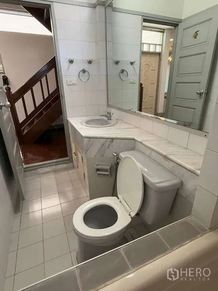 Detached House for rent in Bang Kapi, Bangkok - Compact guest bathroom with long mirror and sink near the staircase.