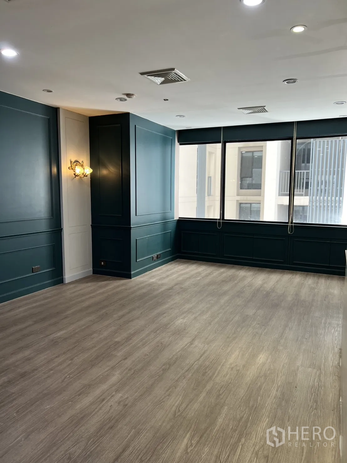 Office Space for rent in Watthana, Bangkok - Bright room with teal paneled walls and large windows.