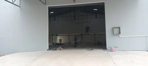 Warehouse for rent in Phra Pradaeng, Samut Prakan - Large warehouse doorway with concrete apron leading into a high-ceiling interior under final touch-ups.