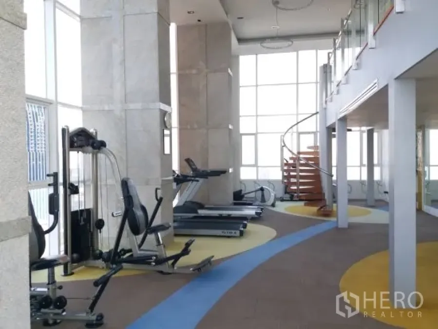 Condominium for rent in Pathum Wan, Bangkok - Light-filled fitness center with cardio machines, weight station and a spiral staircase in a Bangkok condo.