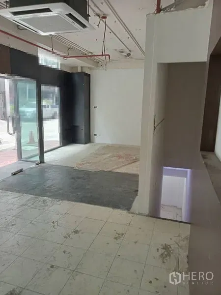 零售空间 出租在Watthana, Bangkok - 临街玻璃门旁的开放式店铺空间，混合地面与顶棚管线。