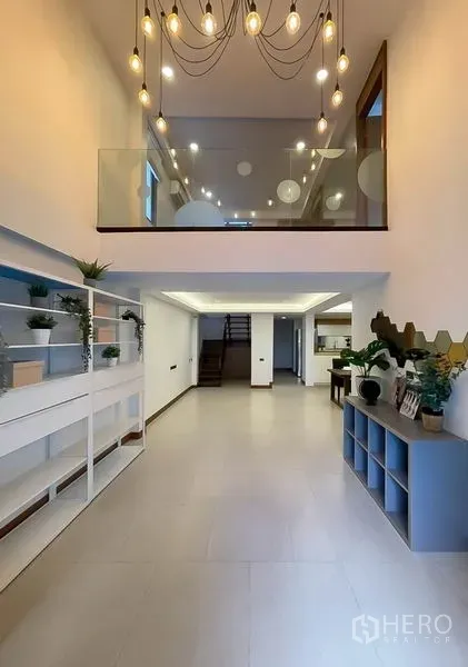 Townhouse for rent in Khlong Toei, Bangkok - Double-height entry hall with pendant lights and glass mezzanine.