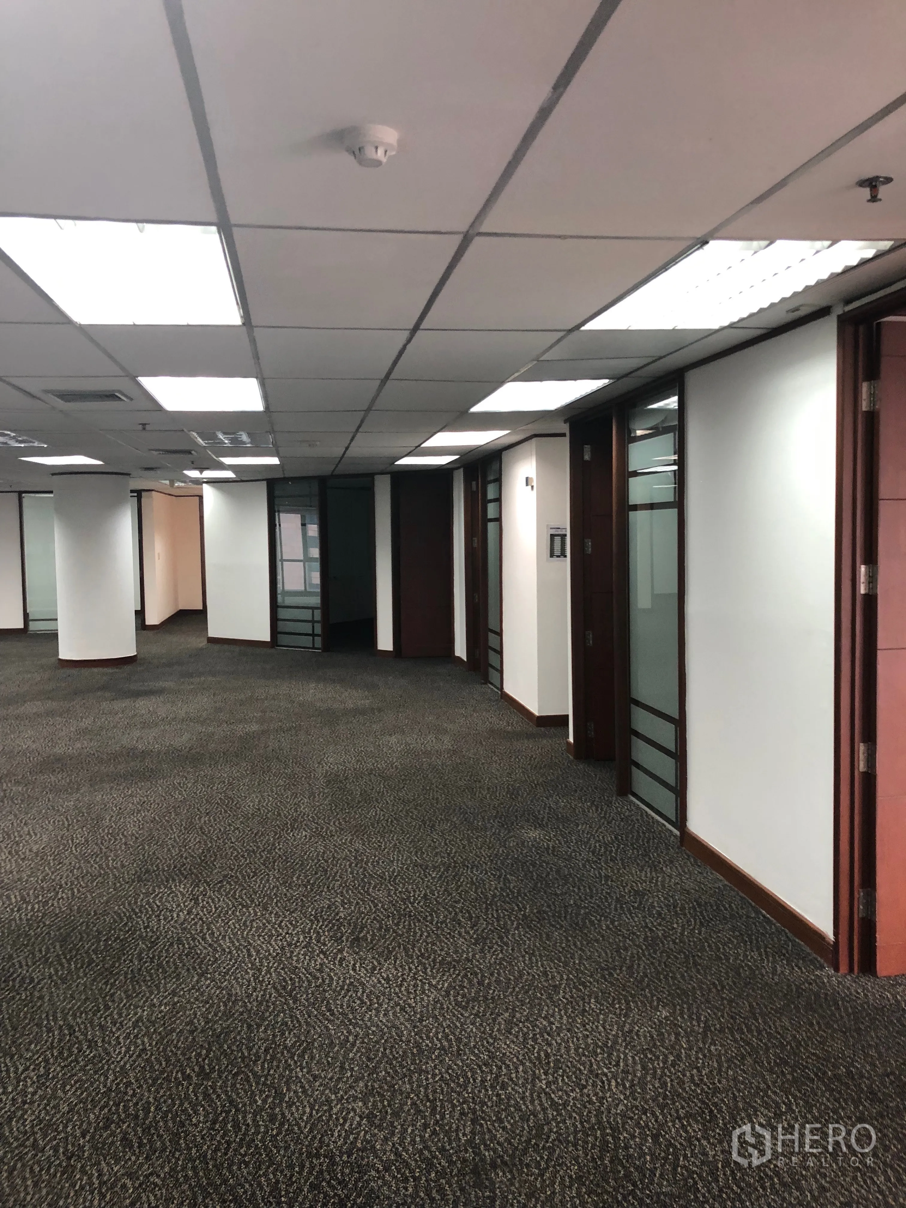 办公空间 出租在Khlong Toei, Bangkok - 办公室走廊视角，多扇玻璃门与木质门框，照明明亮。