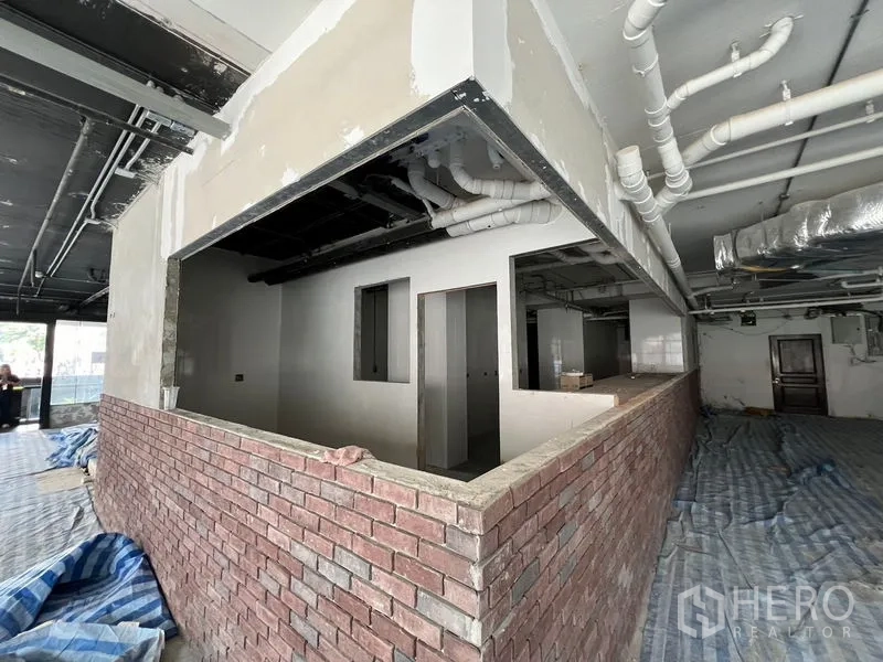 Retail Space for rent in Watthana, Bangkok - Unfinished interior with brick counter, exposed ceiling pipes, and a large open floor plate.
