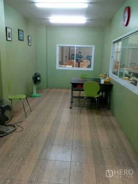Warehouse for rent in Samut Prakan - Air-conditioned office room inside the warehouse with green walls and tile flooring.