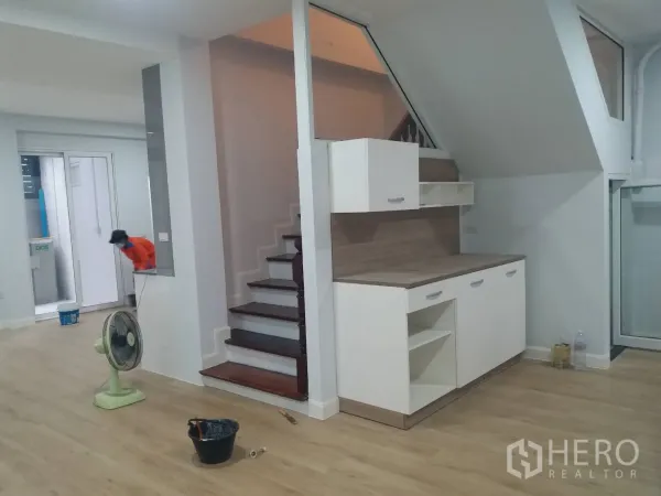 Townhouse for rent in Khlong Toei, Bangkok - Under-stair cabinetry beside a wooden staircase in an open living area with light wood flooring.
