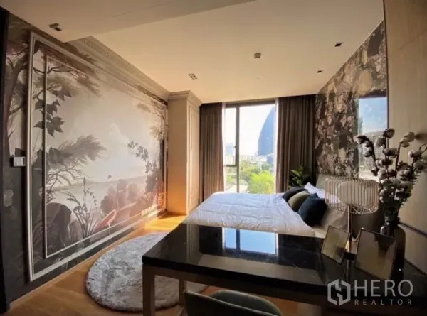 Condominium for rent in Khlong Toei, Bangkok - Bright bedroom with feature mural wall, floor‑to‑ceiling windows, desk and city view.