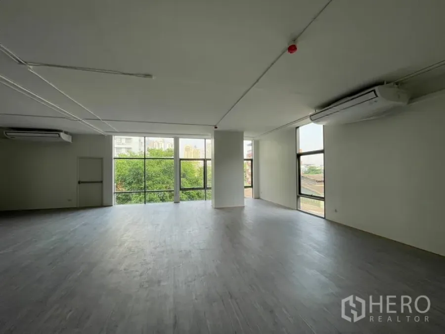 Office Space for rent in Bang Rak, Bangkok - Open-plan 120 sqm office with floor-to-ceiling windows overlooking greenery and city skyline.