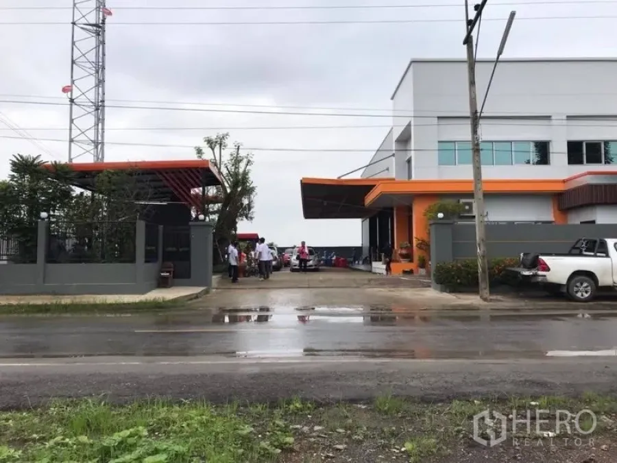 Warehouse for rent in Thanyaburi, Pathum Thani - Street-side view of the compound entrance with wide gate, driveway and perimeter wall.