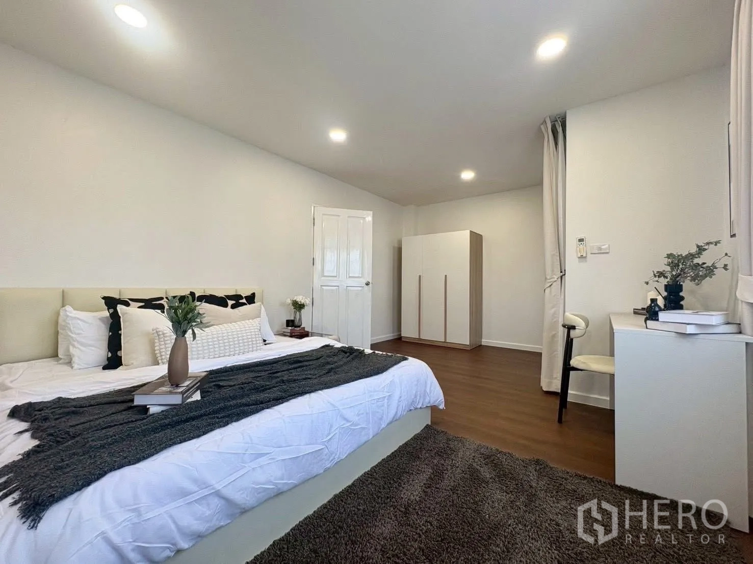 Townhouse for rent in Huai Khwang, Bangkok - Spacious master bedroom with wardrobe, desk, and wood-look flooring.