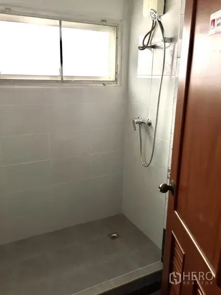 Townhouse for rent in Watthana, Bangkok - Compact tiled bathroom with window and walk-in shower set.