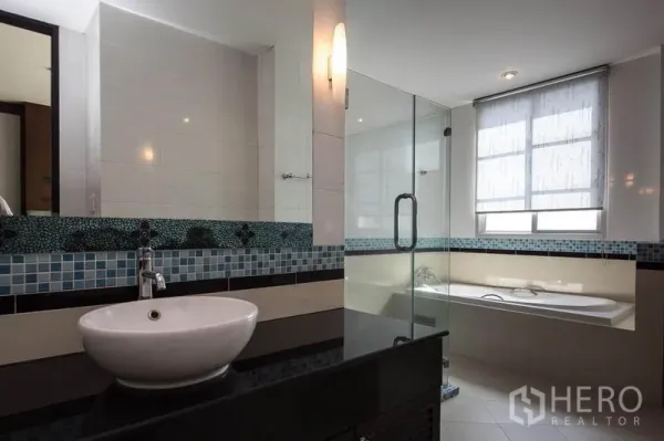 Condominium for rent in Khlong Toei, Bangkok - Modern bathroom featuring a vessel sink with mosaic backsplash, glass shower, and bathtub beside a bright window.