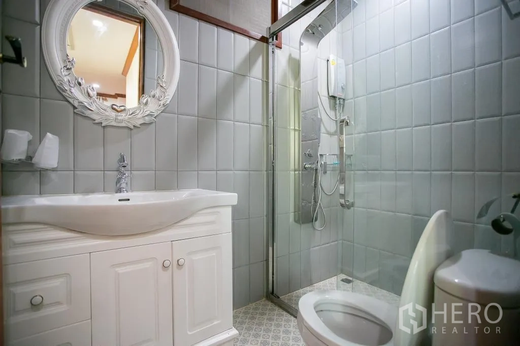 Detached House for rent or sale in Huai Khwang, Bangkok - Second bathroom with white vanity, ornate mirror and glass shower enclosure.