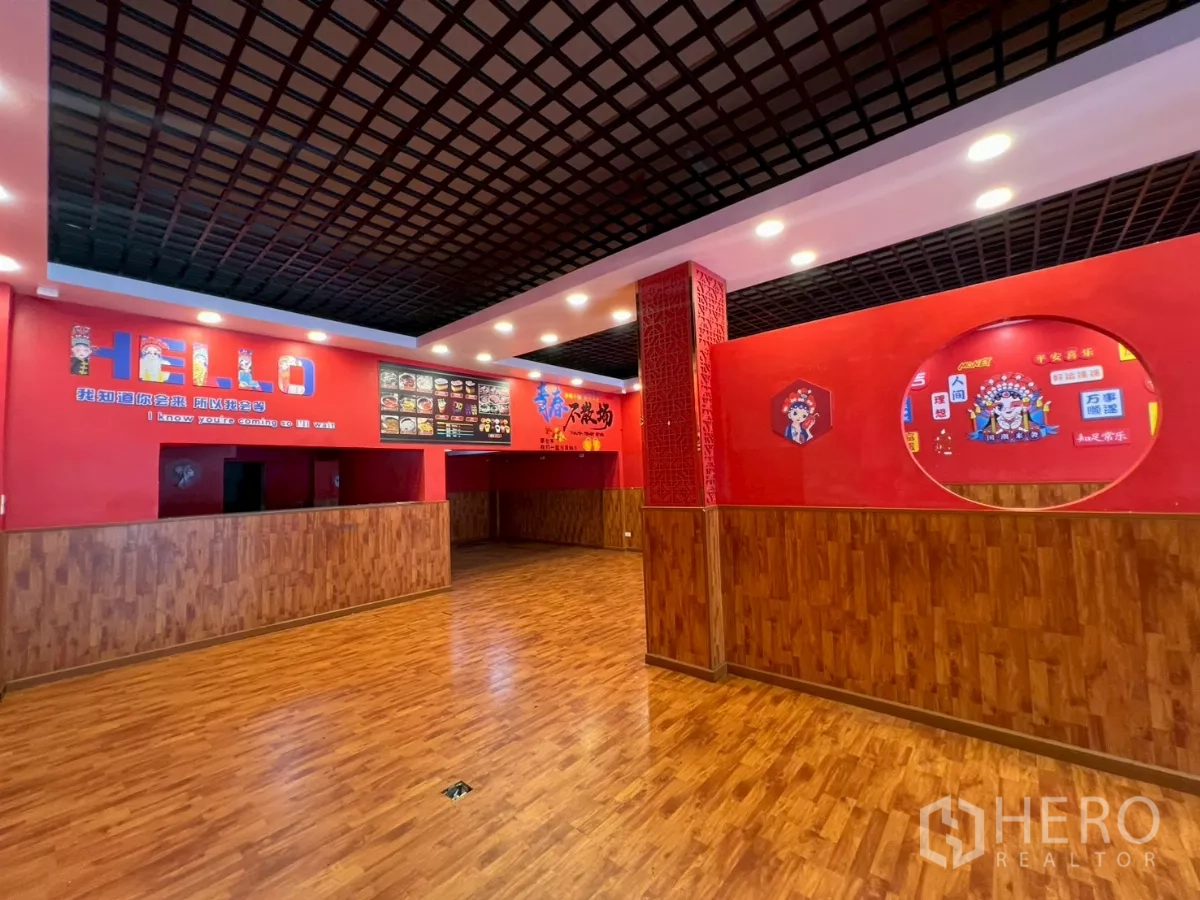 Shophouse for rent in Watthana, Bangkok - Large dining or showroom area with wood floors, red feature columns, and menu boards.