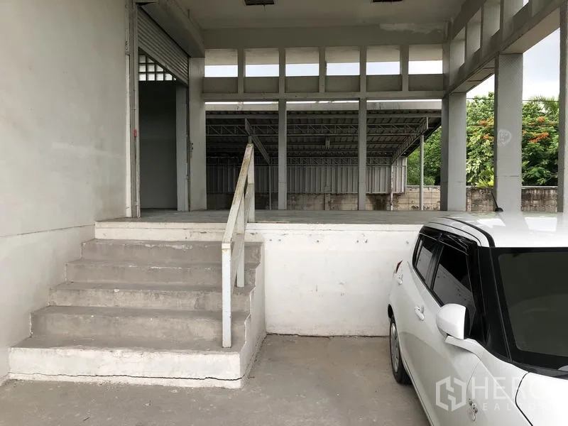 Factory for rent in Lat Krabang, Bangkok - Raised loading platform with steps beside a roller shutter and parking space.